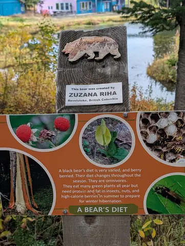 Orange A Bear’s Diet sign under a carved wooden bear plaque, with Brewer’s Pond behind