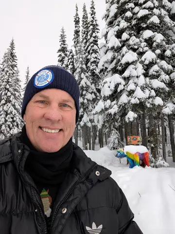 Sean Phillips on the Bear Byway in winter, with the snow-capped rainbow bear behind him