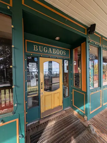 Green-trimmed storefront with a yellow door under the Bugaboos sign