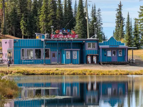 Blue and pink Cafe and Bar building reflected in a pond with golden grass