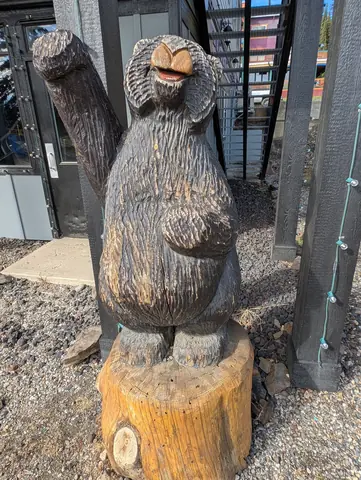 Chainsaw-carved wooden bear on a stump in the village
