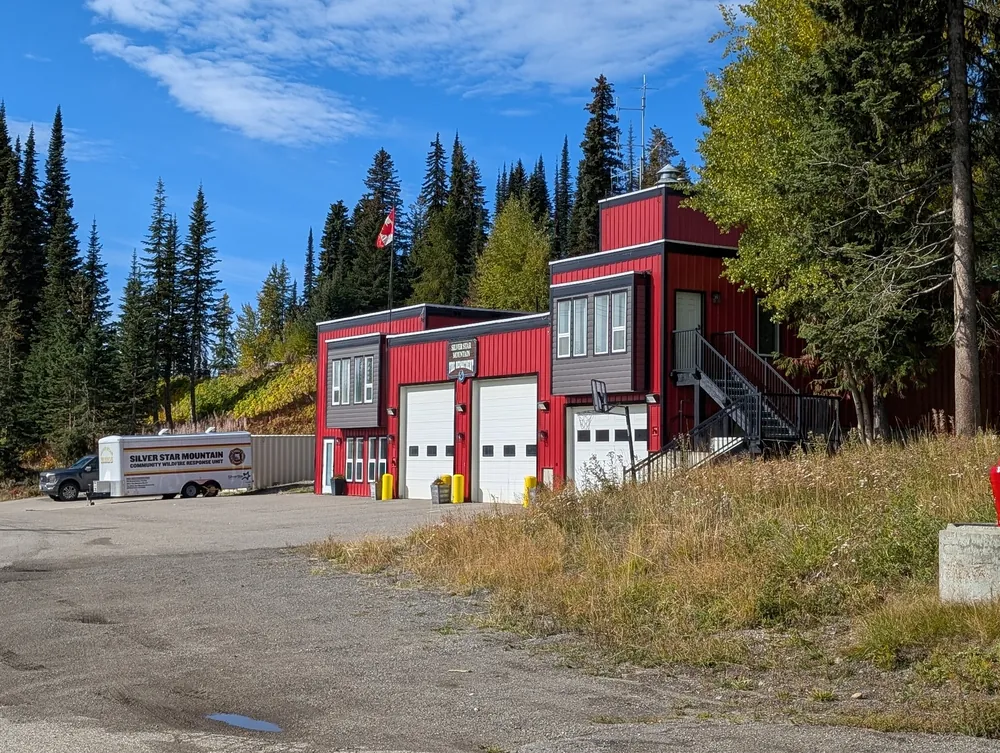Red fire hall with white bay doors among golden aspens