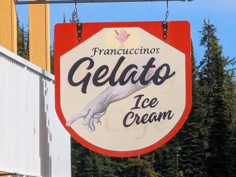 Francuccinos Gelato Ice Cream hanging sign against spruce trees