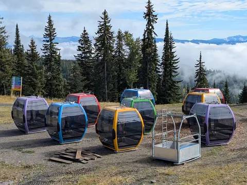 Colourful gondola cabins parked on the hillside above valley cloud in fall