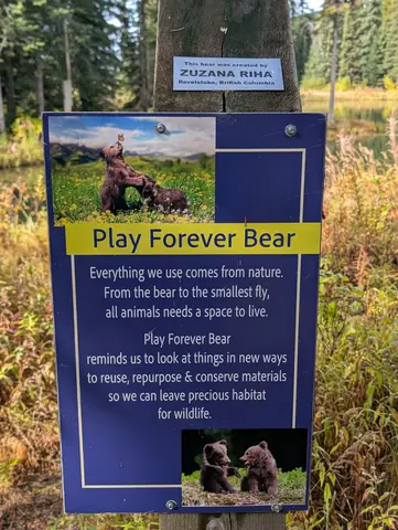 Blue Play Forever Bear sign on a post with a plaque naming Zuzana Riha