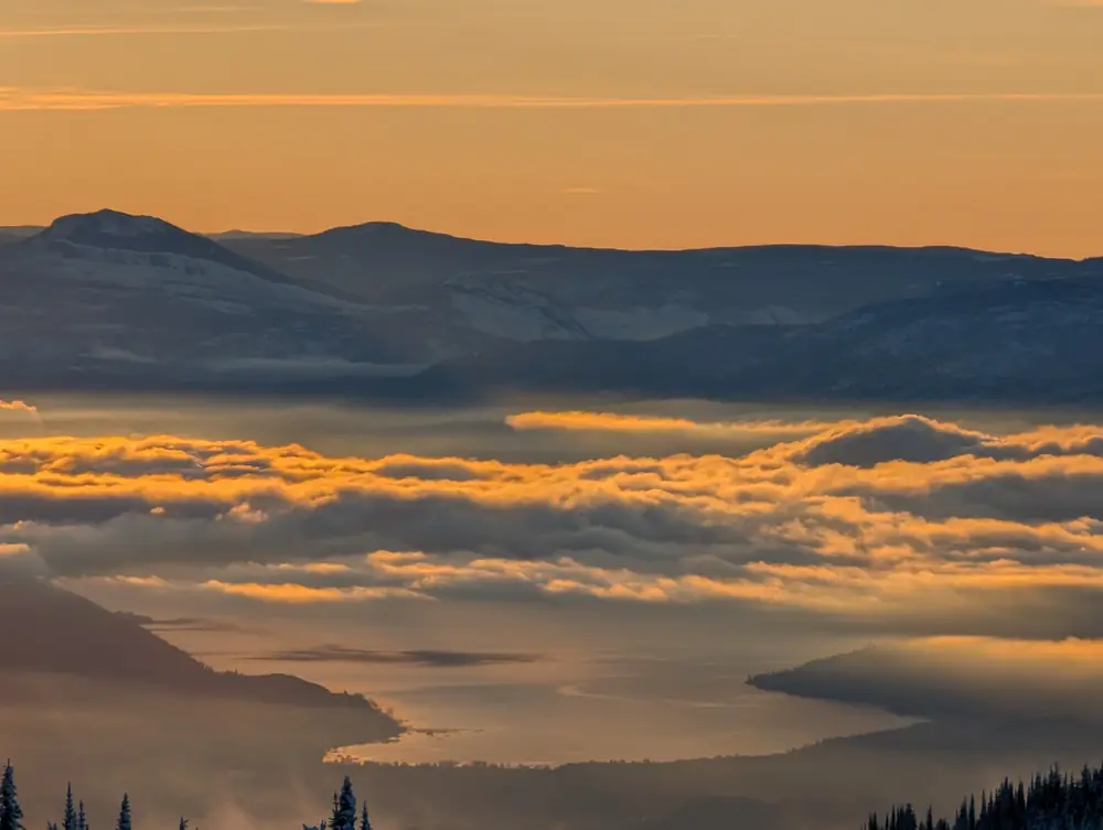 Golden cloud layer filling the valley below SilverStar, with distant mountains and the lake showing through