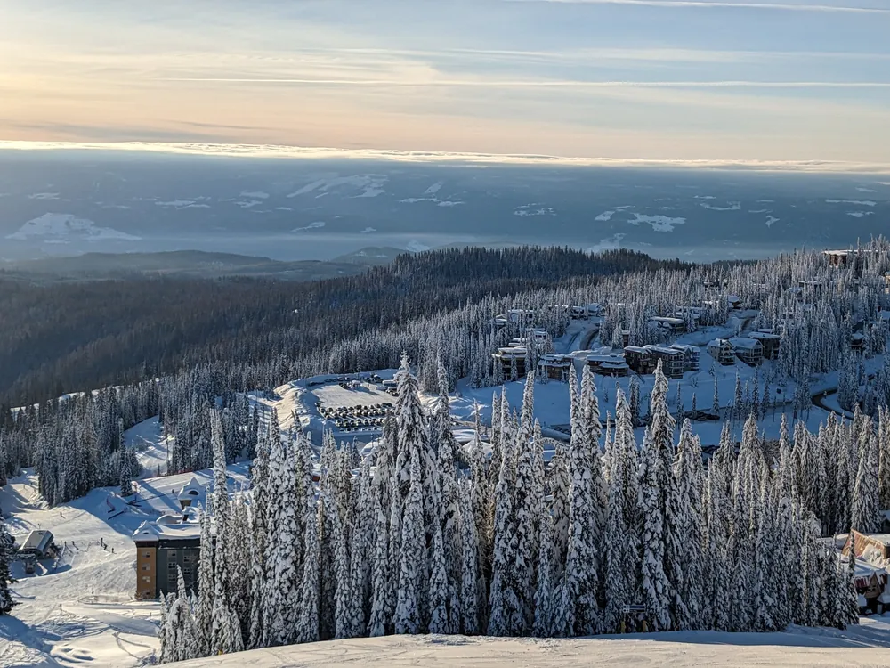 SilverStar village buildings beyond snow-covered trees in golden winter light